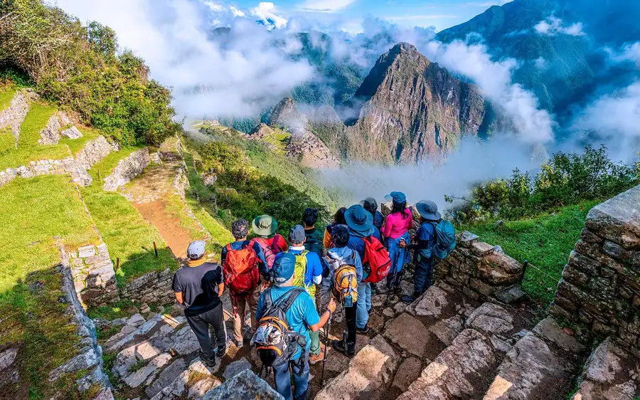 Randonneurs avec sacs à dos sur des marches de pierre au-dessus de montagnes noyées dans les nuages