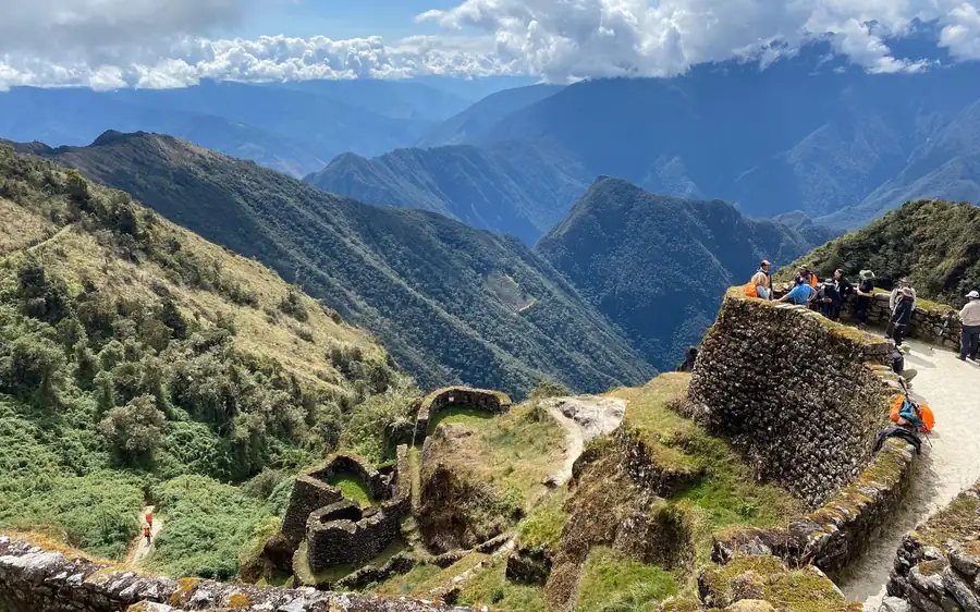 Randonneurs se reposant près d'une ruine de pierre sur une crête au-dessus de vallées montagneuses boisées