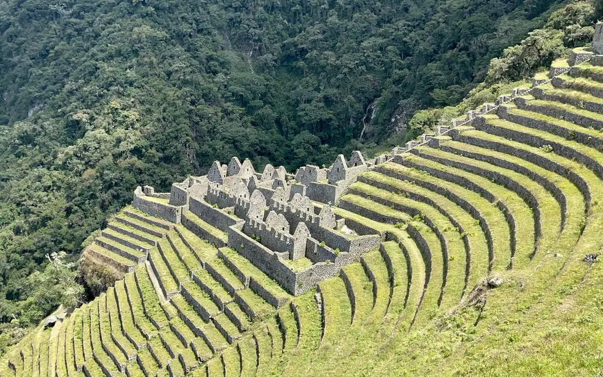 Ruines de pierre et terrasses courbes sur une pente boisée escarpée